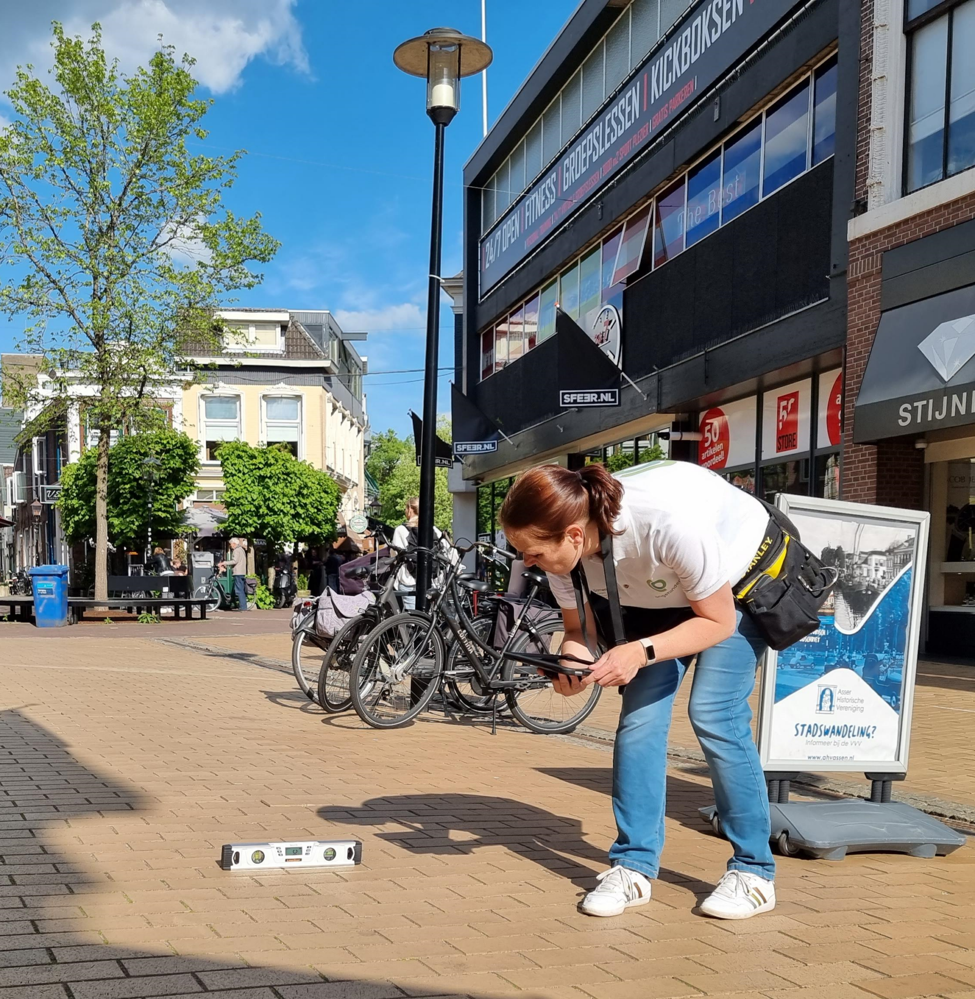 Een inspecteur toegankelijkheid die met een waterpas de openbare ruimte toetst