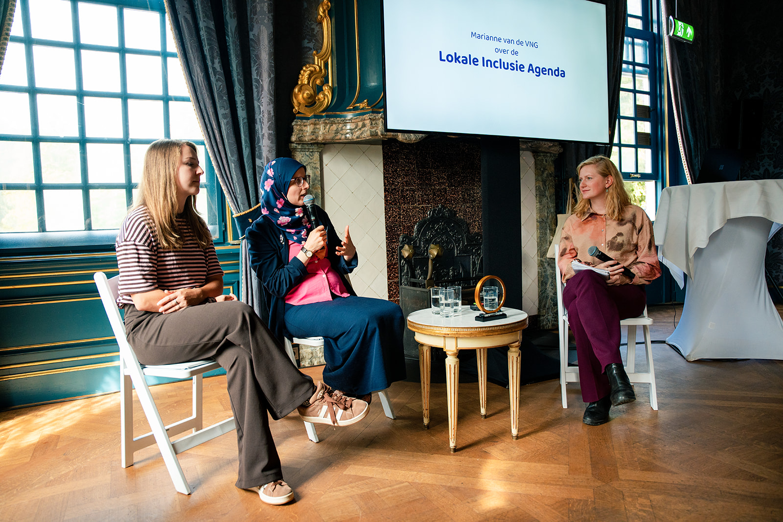 Drie dames zittend op een rijtje in gesprek met elkaar